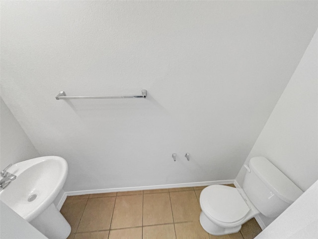 half bath featuring tile patterned flooring, baseboards, and toilet