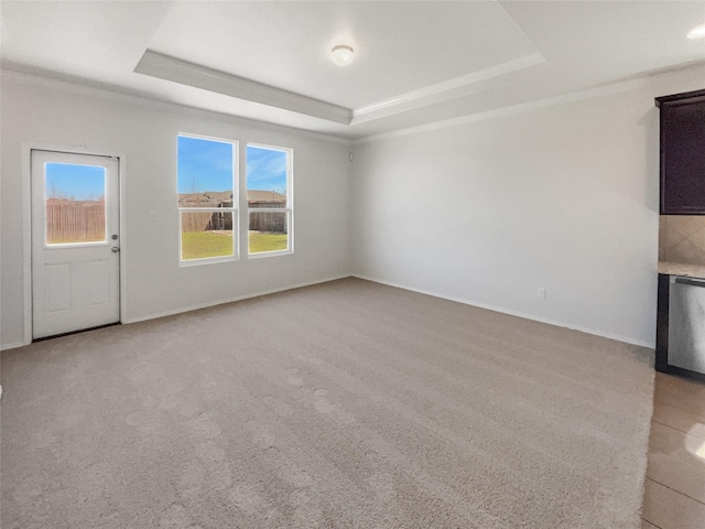 unfurnished living room with a tray ceiling, light carpet, and baseboards