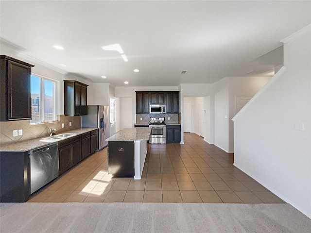 kitchen featuring stainless steel appliances, a kitchen island, a sink, dark brown cabinets, and tasteful backsplash