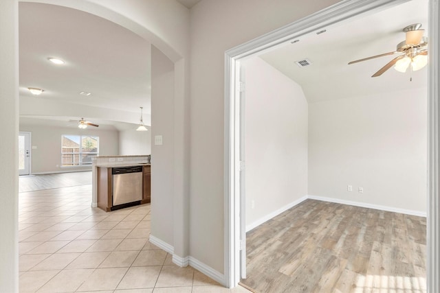 hall with arched walkways, visible vents, baseboards, and light tile patterned floors