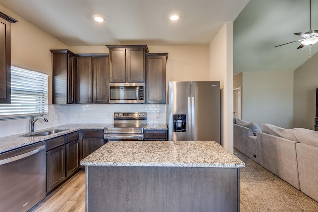 kitchen with dark brown cabinets, stainless steel appliances, a sink, and open floor plan