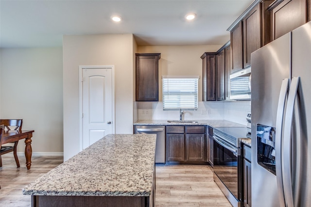 kitchen with stainless steel appliances, backsplash, light wood-style floors, a sink, and dark brown cabinetry