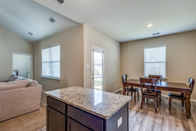 kitchen featuring light wood-type flooring, plenty of natural light, visible vents, and lofted ceiling