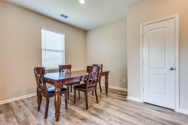 dining space featuring light wood-style flooring, visible vents, and baseboards