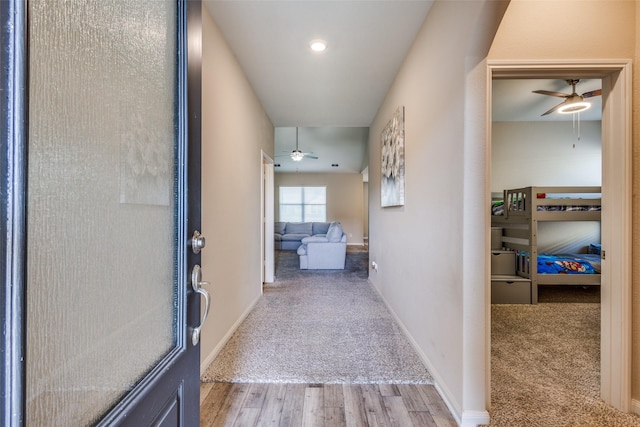 hall with carpet floors, wood finished floors, and baseboards