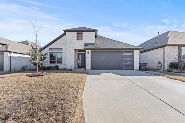 view of front of house featuring driveway, a shingled roof, an attached garage, a front lawn, and brick siding