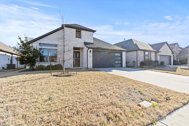 view of front of house featuring a front lawn, concrete driveway, brick siding, and an attached garage