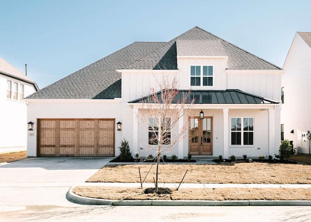 modern farmhouse style home featuring metal roof, an attached garage, driveway, french doors, and a standing seam roof