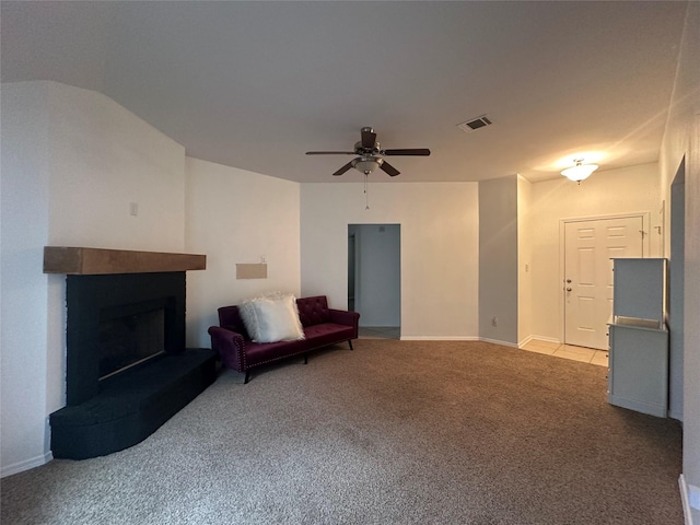 unfurnished room featuring visible vents, a fireplace with raised hearth, a ceiling fan, carpet flooring, and baseboards