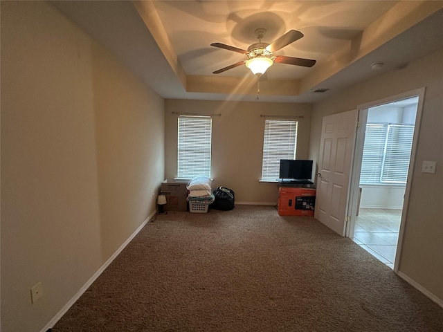 interior space featuring carpet flooring, baseboards, a raised ceiling, and visible vents