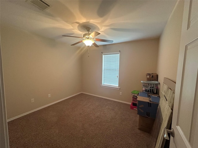 spare room featuring visible vents, baseboards, a ceiling fan, and dark colored carpet