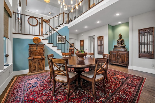 dining space featuring stairs, wood finished floors, a towering ceiling, and baseboards