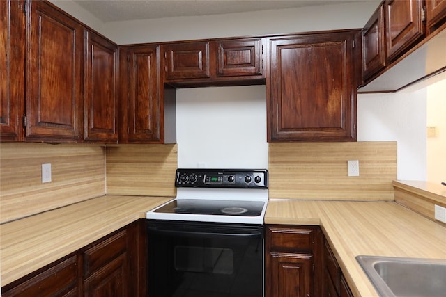 kitchen with dark brown cabinetry, tasteful backsplash, range with electric cooktop, and light countertops