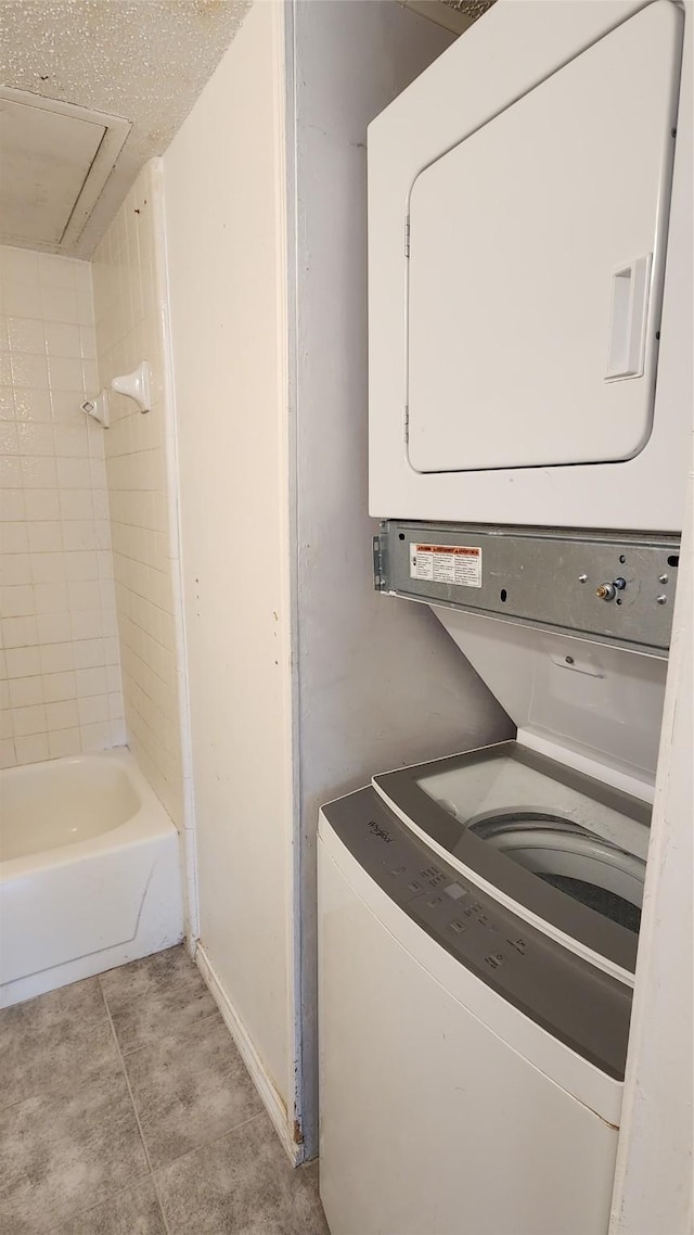 laundry area with attic access, stacked washer / dryer, laundry area, and light tile patterned floors