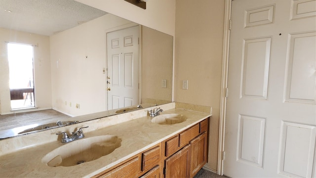 bathroom with a textured ceiling, double vanity, and a sink