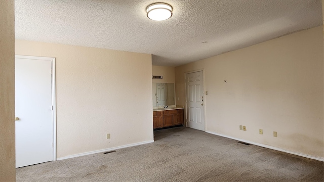 unfurnished bedroom featuring baseboards, a textured ceiling, visible vents, and carpet flooring