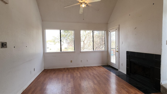 unfurnished living room featuring baseboards, a ceiling fan, wood finished floors, vaulted ceiling, and a fireplace