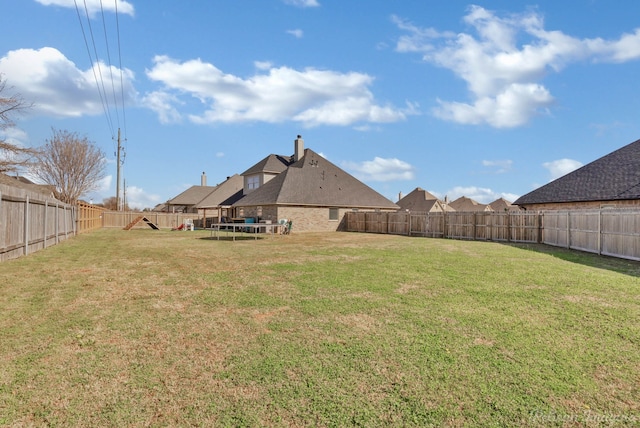 view of yard featuring a trampoline and a fenced backyard