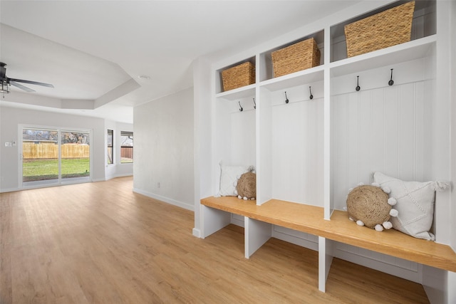 mudroom featuring light wood-style floors, a tray ceiling, baseboards, and a ceiling fan