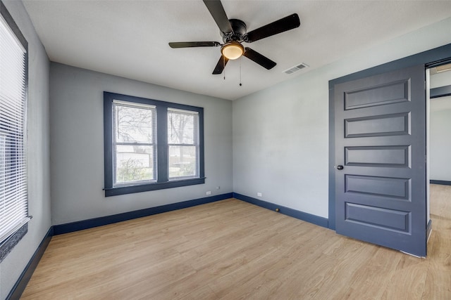 empty room with a ceiling fan, baseboards, visible vents, and light wood finished floors