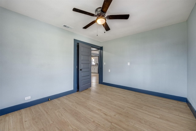 spare room with ceiling fan, wood finished floors, visible vents, and baseboards