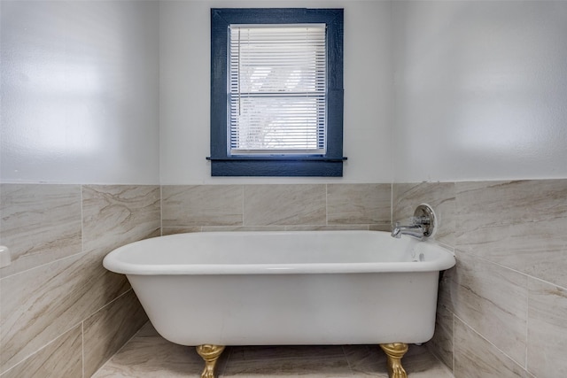 bathroom with a freestanding bath, a wainscoted wall, and tile walls