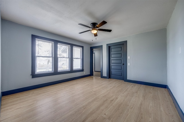 unfurnished room featuring light wood-style flooring, baseboards, ceiling fan, and a textured ceiling