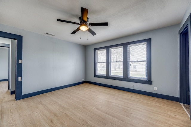 unfurnished room with light wood-style flooring, visible vents, baseboards, and a ceiling fan