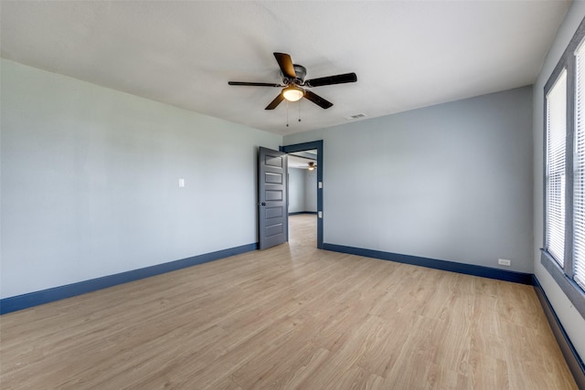 spare room with a ceiling fan, visible vents, light wood-style flooring, and baseboards