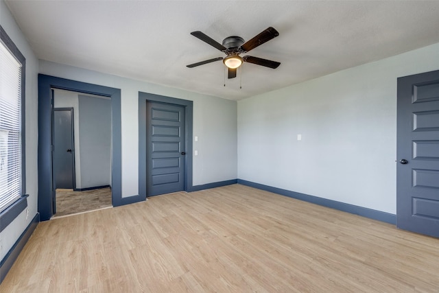 unfurnished bedroom featuring ceiling fan, light wood-style flooring, and baseboards