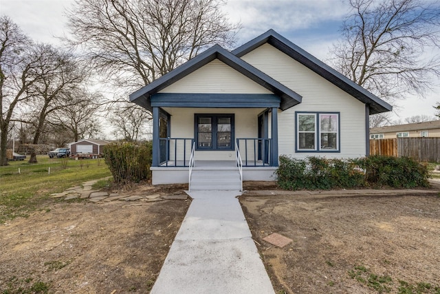 bungalow-style house with covered porch and fence