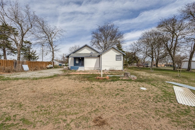 rear view of property featuring a lawn and fence