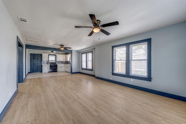 unfurnished living room featuring light wood finished floors, baseboards, visible vents, and a ceiling fan