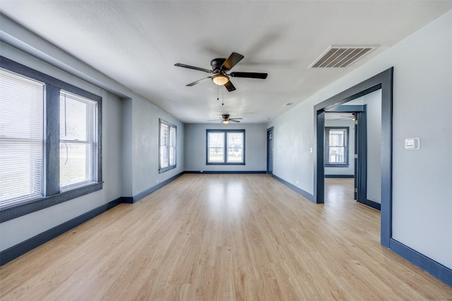 empty room featuring light wood-style flooring, visible vents, and baseboards