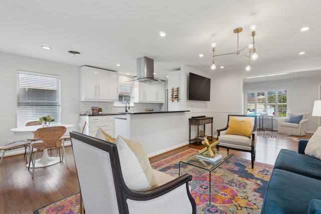 living area with baseboards, wood finished floors, and recessed lighting