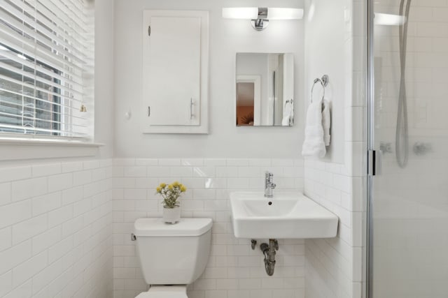 full bathroom featuring toilet, a stall shower, a sink, and tile walls