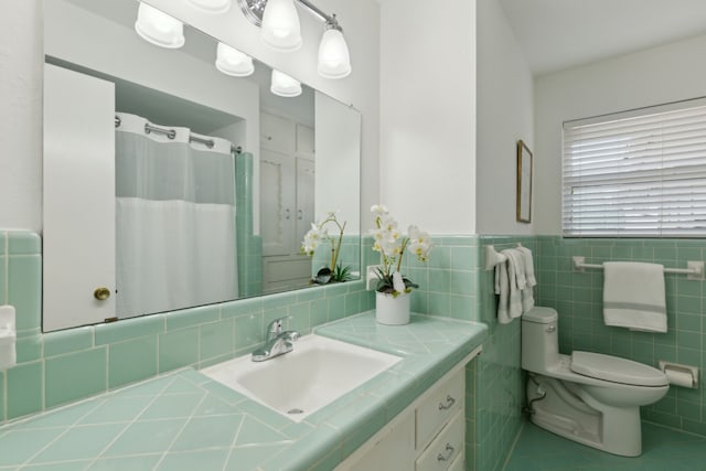 full bath with toilet, a shower with shower curtain, vanity, tile walls, and wainscoting