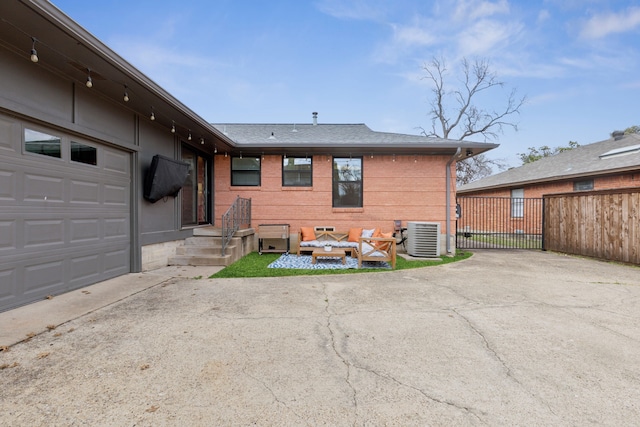 exterior space with a garage, central AC, brick siding, fence, and concrete driveway