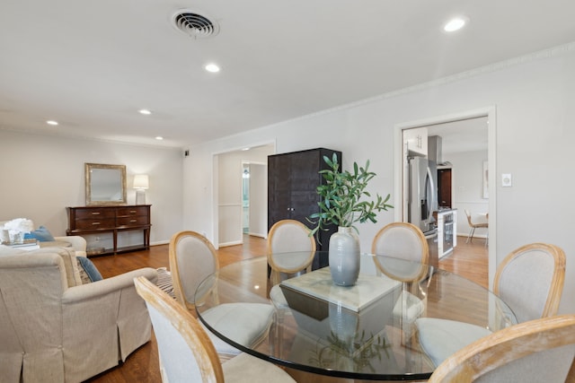 dining area with ornamental molding, wood finished floors, visible vents, and recessed lighting