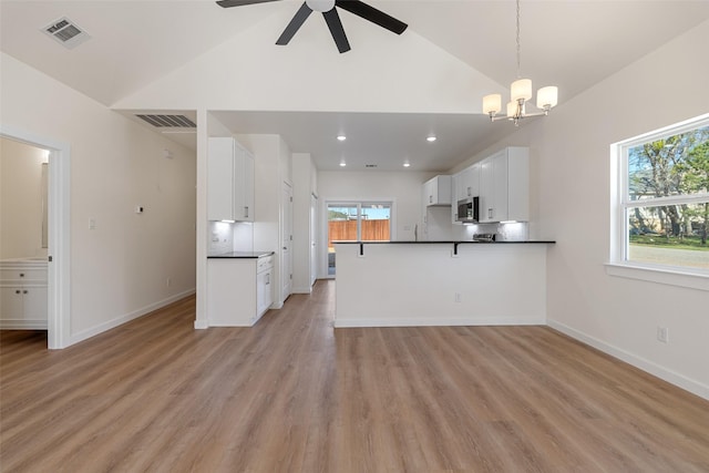 kitchen featuring a peninsula, white cabinetry, visible vents, and stainless steel microwave