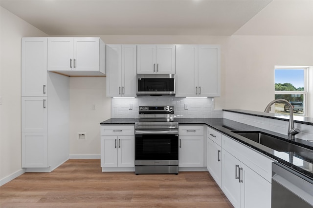 kitchen with stainless steel appliances, white cabinetry, a sink, and light wood finished floors