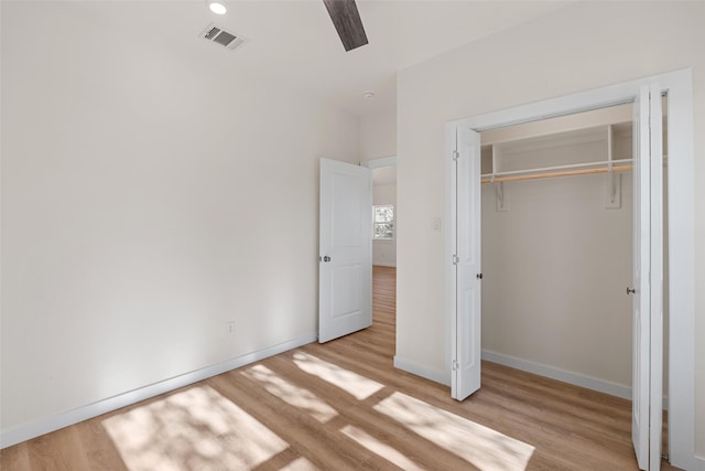 unfurnished bedroom featuring light wood-style flooring, visible vents, baseboards, and a closet