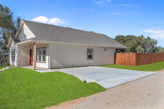 exterior space featuring a yard, roof with shingles, a patio area, and fence