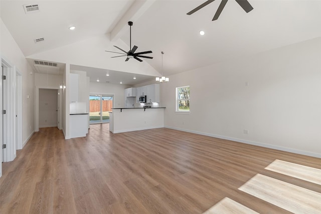 unfurnished living room with a wealth of natural light, visible vents, beamed ceiling, and light wood finished floors