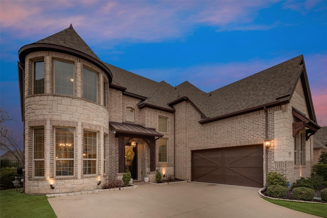 french country style house with brick siding, roof with shingles, an attached garage, metal roof, and driveway