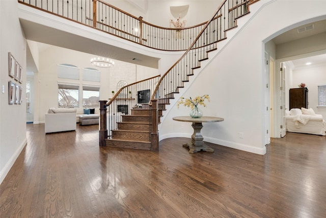 entryway with baseboards, visible vents, a high ceiling, and wood finished floors