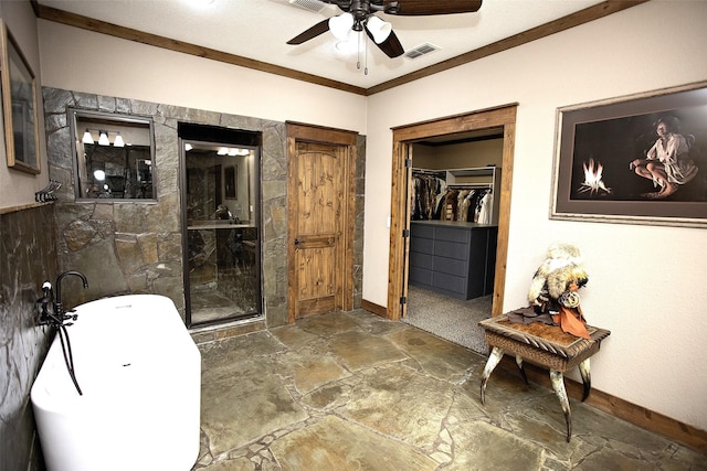 full bathroom featuring crown molding, stone tile flooring, visible vents, a freestanding tub, and baseboards