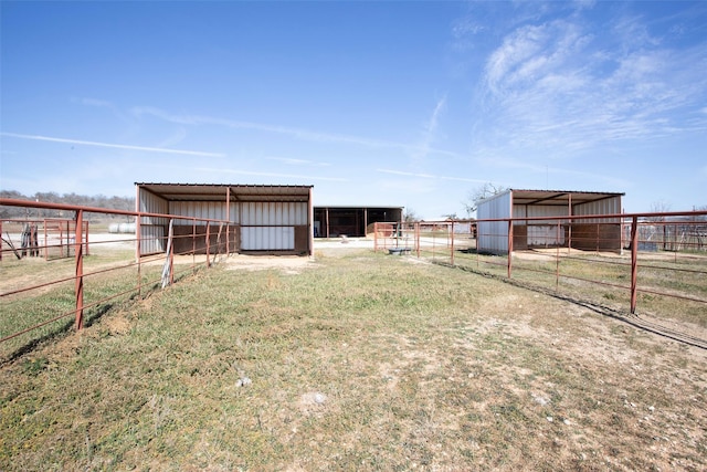 view of yard with an outbuilding, a rural view, an exterior structure, and a detached carport