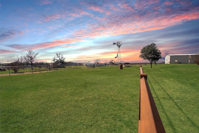 view of home's community with a rural view, fence, and a yard