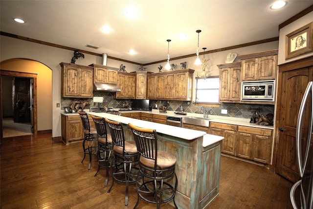 kitchen with arched walkways, visible vents, appliances with stainless steel finishes, a kitchen island, and under cabinet range hood